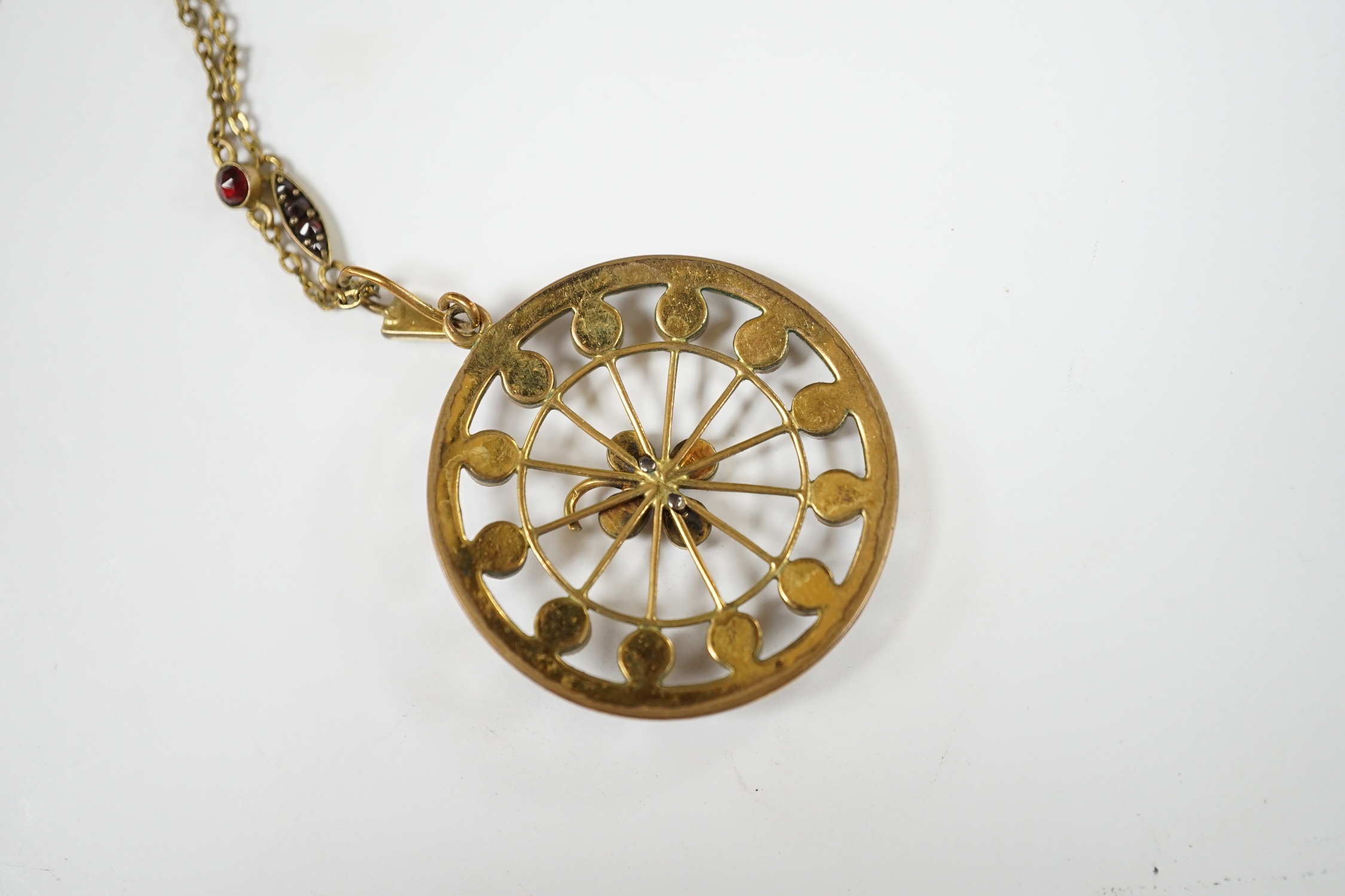 A late Victorian gilt metal and garnet cluster set 'wheel' pendant on a garnet set chain, overall 48cm. Condition - poor to fair